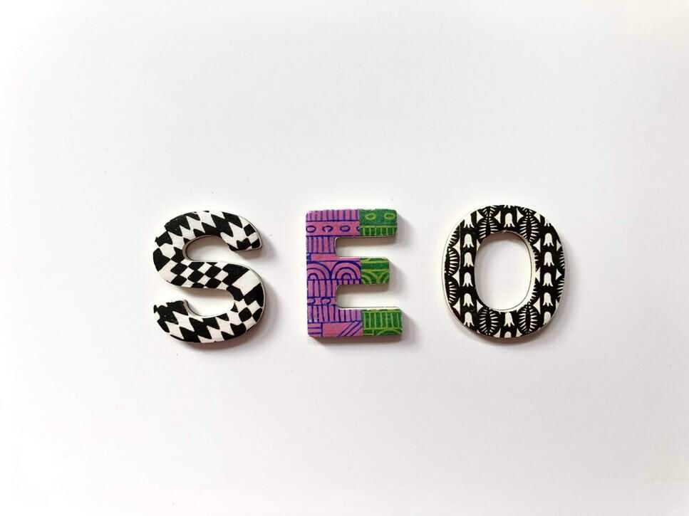 De letters SEO in drie gedecoreerde houten letters op een witte ondergrond