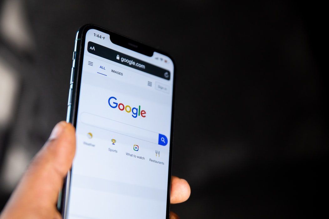 Een hand houdt een telefoon vast met de zoekpagina van Google geopend